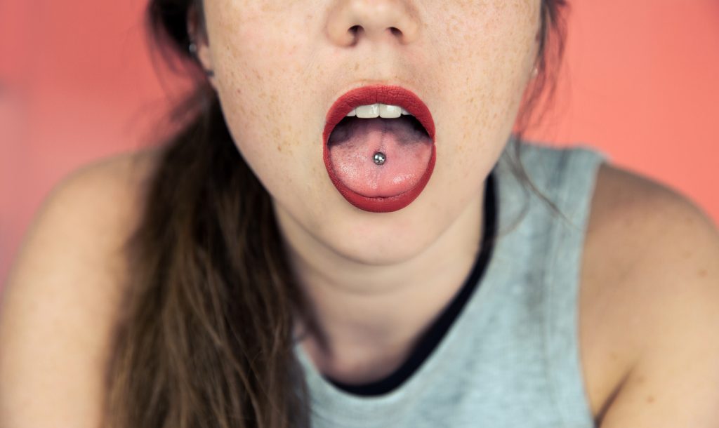 Young woman with a tongue piercing.