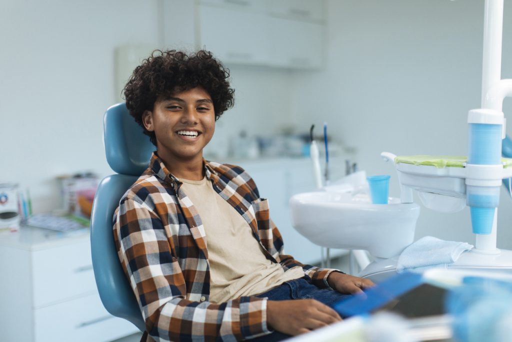 Male teen smiling in dental chair ready for wisdom tooth extraction